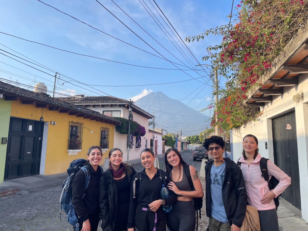 A group of people standing on a street with backpacks and handbags.